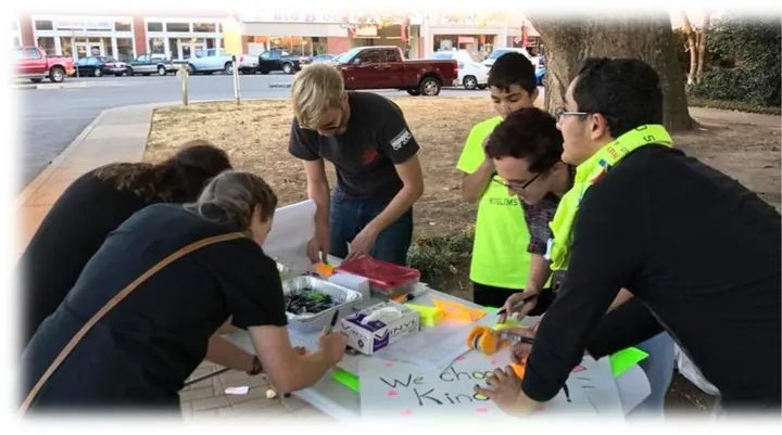 MMY youth making signs at an outdoor community table, 2016