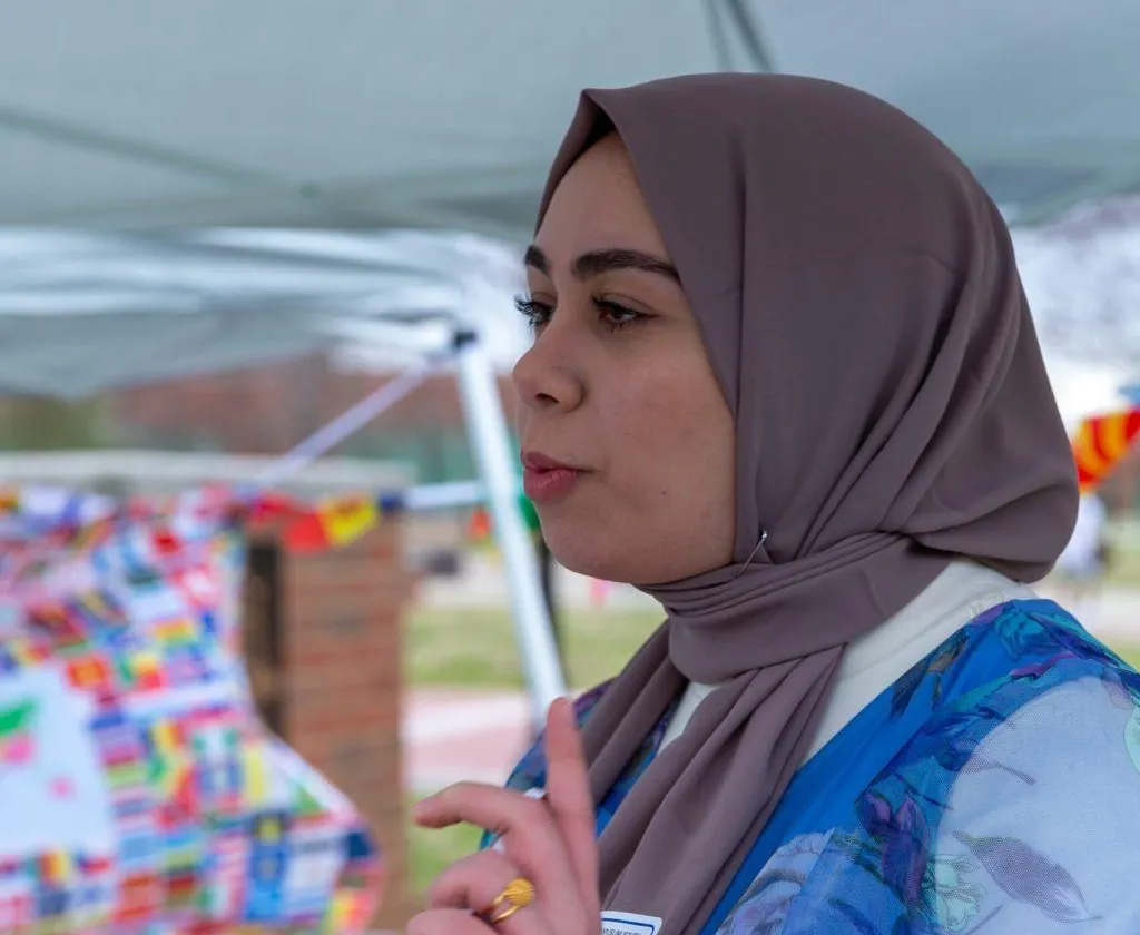 An MMY team member speaking with visitors at an MMY outreach tent