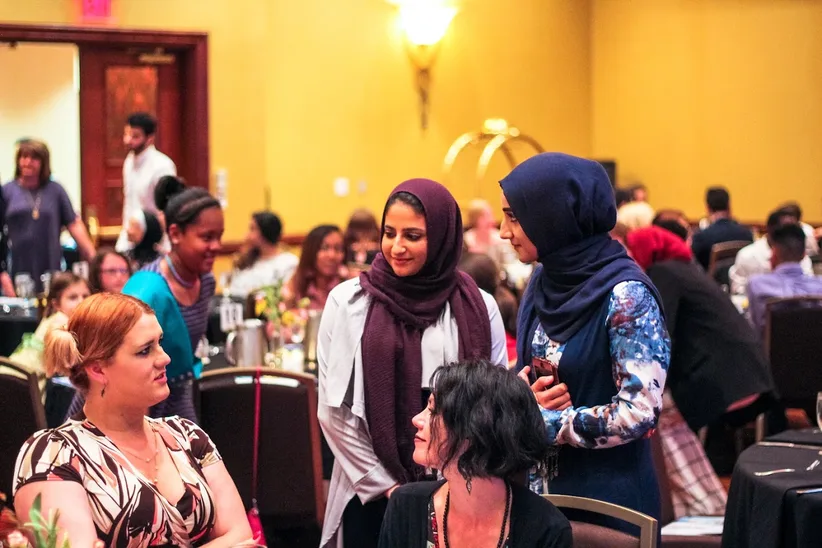 MMY leaders Sarah Alzabet and Haneen Ahmad talking with a guest at the Appreciation Iftar