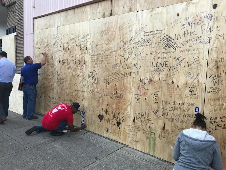 Community members writing messages of acceptance on plywood storefront coverings in downtown Murfreesboro, October 2017