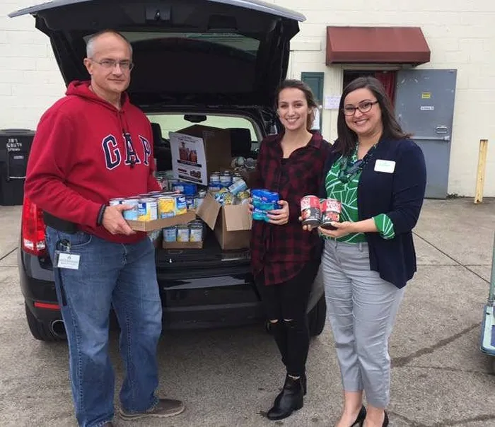 Volunteers loading donated food into a car trunk