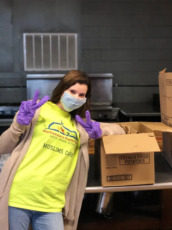 A masked MMY volunteer boxing supplies during the COVID-19 response